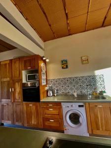 a kitchen with a washing machine and a microwave at Chambre et SDB privative Ylang Ylang vue Mont Pelée dans maison partagée in Le Morne Rouge +7 photos