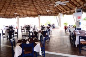 a dining room with tables and chairs and a ceiling at Departamento junto a Las Hadas Manzanillo in Manzanillo