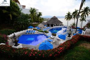 a swimming pool with blue chairs and umbrellas at Departamento junto a Las Hadas Manzanillo in Manzanillo
