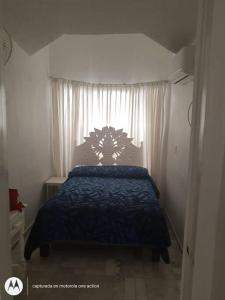 1 dormitorio con 1 cama con edredón azul y ventana en Departamento junto a las hadas manzanillo en Manzanillo