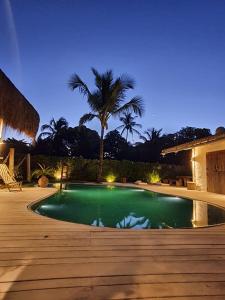 - une piscine avec un palmier en arrière-plan la nuit dans l'établissement Villa Fulô, à Caraíva