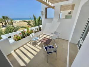 a balcony with chairs and tables and the beach at Beachfront Apartment - Andalucia in Bizerte