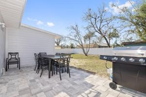 a patio with a table and chairs and a grill at Nature's Coast Retreat in Spring Hill