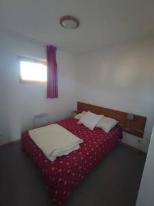 Schlafzimmer mit einem Bett mit roter Bettwäsche und einem Fenster in der Unterkunft Appartement 10 personnes au pied des pistes - Superdévoluy in Superdevoluy