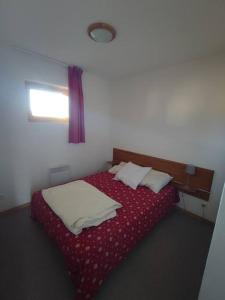 a bedroom with a bed with red sheets and a window at Appartement 10 personnes au pied des pistes - Superdévoluy in Superdevoluy