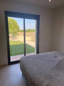 - une chambre avec un lit et une grande porte en verre dans l'établissement Le nid d'Emilie, à Maillane