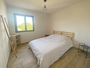um quarto branco com uma cama e uma janela em Le nid d'Emilie em Maillane