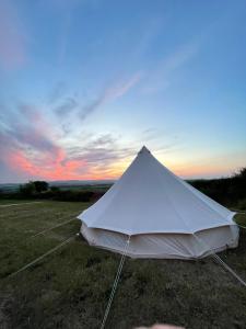 ein weißes Zelt auf einem Feld mit Sonnenuntergang in der Unterkunft Wheeldon Escapes in Totnes