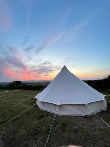 una tienda blanca en un campo con puesta de sol en Wheeldon Escapes en Totnes