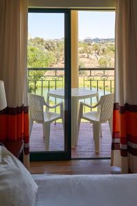 a room with a bed and a table and chairs on a balcony at The Navigator - Palm Oasis Alvor - All Inclusive in Alvor