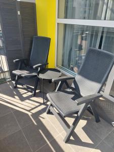 3 cadeiras sentadas numa varanda com uma janela em Apartament HAMPTONS Gdynia em Gdynia
