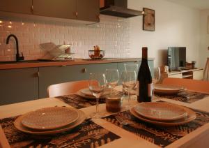 a table with a bottle of wine and glasses on it at Les appartements de Clélia in Ax-les-Thermes