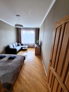 a bedroom with a bed and a living room with a couch at Great View Meridianas Apartment in Klaipėda