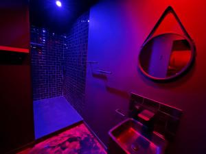 baño con lavabo y espejo con luces moradas en Le Maquis Rooms en Plan dʼAups