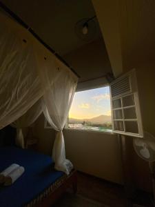 a bedroom with a bed and a window with a view at Chambre Ylang Ylang vue Mont Pelée in Le Morne Rouge