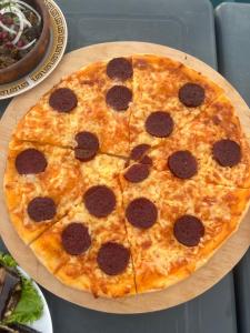 une pizza pepperoni assise sur un panneau en bois dans l'établissement Inn David, à Chakvi