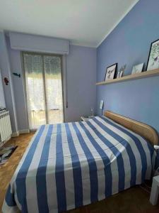um quarto azul com uma cama listrada em azul e branco em Colibrì, vicino a pineta e mare em Viareggio