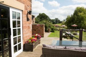 eine Terrasse mit einem Tisch und Blumen auf einem Gebäude in der Unterkunft Alvanley Arms, Cotebrook in Tarporley