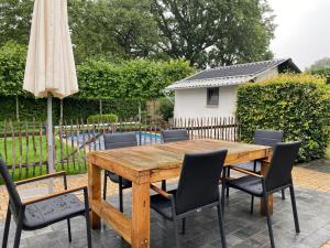 a wooden table with chairs and an umbrella at Beautiful Villa with swimming pool in Zonhoven in Genk