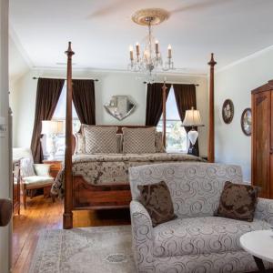 a bedroom with a bed and a couch and a chandelier at Black Walnut B&B Inn in Asheville