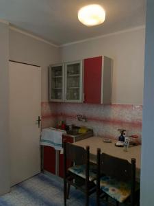 una cocina con armarios rojos y una mesa con sillas. en Seoska Kuća, en Cetinje