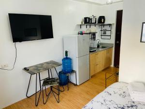 a small kitchen with a refrigerator and a table with a sink at Stylish comfy studio and workspace in Cebu City