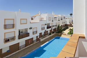 un appartamento con piscina di fronte a un edificio di Cabanas Terrace a Cabanas de Tavira