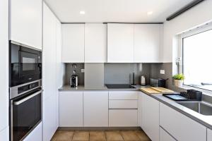 una cucina bianca con mobili bianchi e una finestra di Cabanas Terrace a Cabanas de Tavira