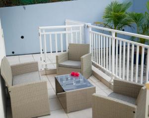 a balcony with chairs and a table and a white railing at Rubis Appartement - Magnifique F3 in Sainte-Anne