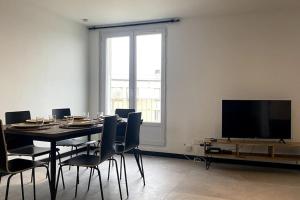 une salle à manger avec une table, des chaises et une télévision dans l'établissement * 3 Chambres - Haut de gamme - proche Paris *, à Villejuif