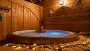 un uomo nella vasca da bagno in una stanza di legno di Le Village de la Champagne - Slowmoov a Bar-sur-Aube