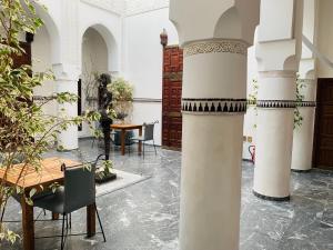 Zimmer mit einem Tisch und Stühlen sowie einer Säule in der Unterkunft Palais Aix Kabaj &Spa in Marrakesch