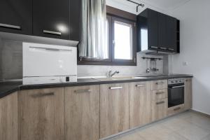 eine Küche mit Holzschränken, einem Waschbecken und einem Fenster in der Unterkunft #Luxlikehome Seashell Villa in Posidi