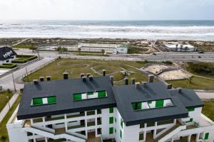 a building on the beach with the ocean in the background at Casa dos Patos Quiaios in Figueira da Foz