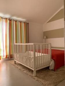 een kinderkamer met een wieg en een rood bed bij Casa dos Patos Quiaios in Figueira da Foz