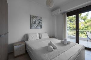 Schlafzimmer mit einem Bett mit weißer Bettwäsche und einem Fenster in der Unterkunft #Luxlikehome Seashell Villa in Posidi