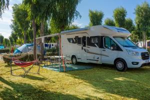 une camionnette blanche garée dans l'herbe avec une tente dans l'établissement Camping Village Laguna Blu, à Fertilia