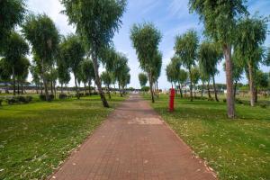 a brick path in a park with trees and a red fire hydrant at Camping Village Laguna Blu in Fertilia