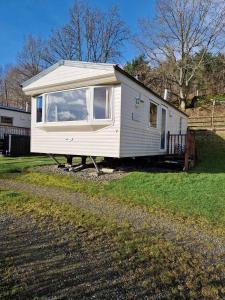 a small white tiny house in a yard at Cruachan Caravan and Camping Farm in Killin