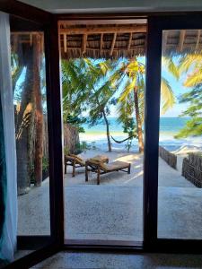 Blick aus einem Fenster auf einen Strand mit Bänken in der Unterkunft Blue Palm Zanzibar in Bwejuu