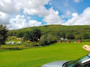 a green field with a hill in the background at Cruachan Caravan and Camping Farm in Killin