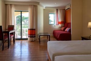 a hotel room with a bed and a couch and a table at The Navigator - Palm Oasis Alvor - All Inclusive in Alvor