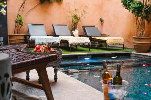 Palais Aix Kabaj &Spa في مراكش: حمام سباحة مع طاولة وزجاجتين من النبيذ