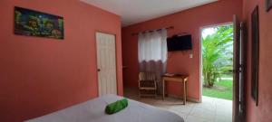 a bedroom with orange walls and a bed and a window at Hotel Munch in Managua