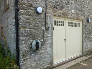 a stone building with a white door and a wall at The Old Map Shop in Wigton