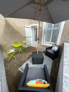 een patio met een parasol, stoelen en een tafel bij Logement entier: Appartement avec Terrasse Quartier de la Gare in Amboise