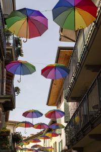a bunch of colorful umbrellas hanging from buildings at Casa San Marco in Pisogne