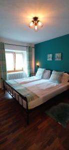 a large bed in a bedroom with a blue wall at Gasthof Zum Lugauer in Radmer an der Hasel