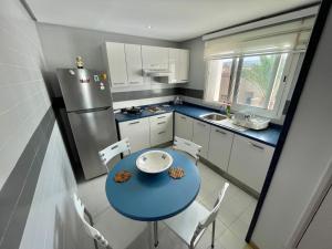 Beachfront Apartment - Andalucia في بنزرت: مطبخ صغير مع طاولة زرقاء وثلاجة
