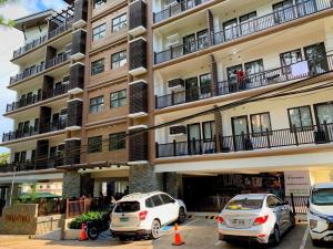 two cars parked in a parking lot in front of a building at Cozynest Condotel Baguio in Baguio
